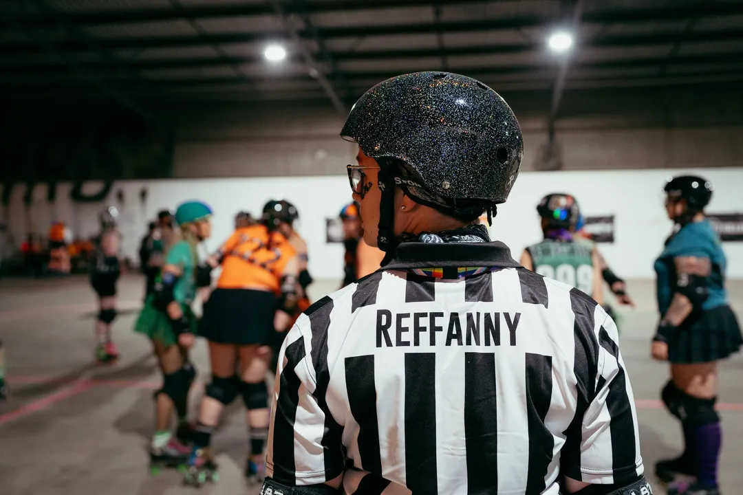 A referee in a striped jersey watches the jam